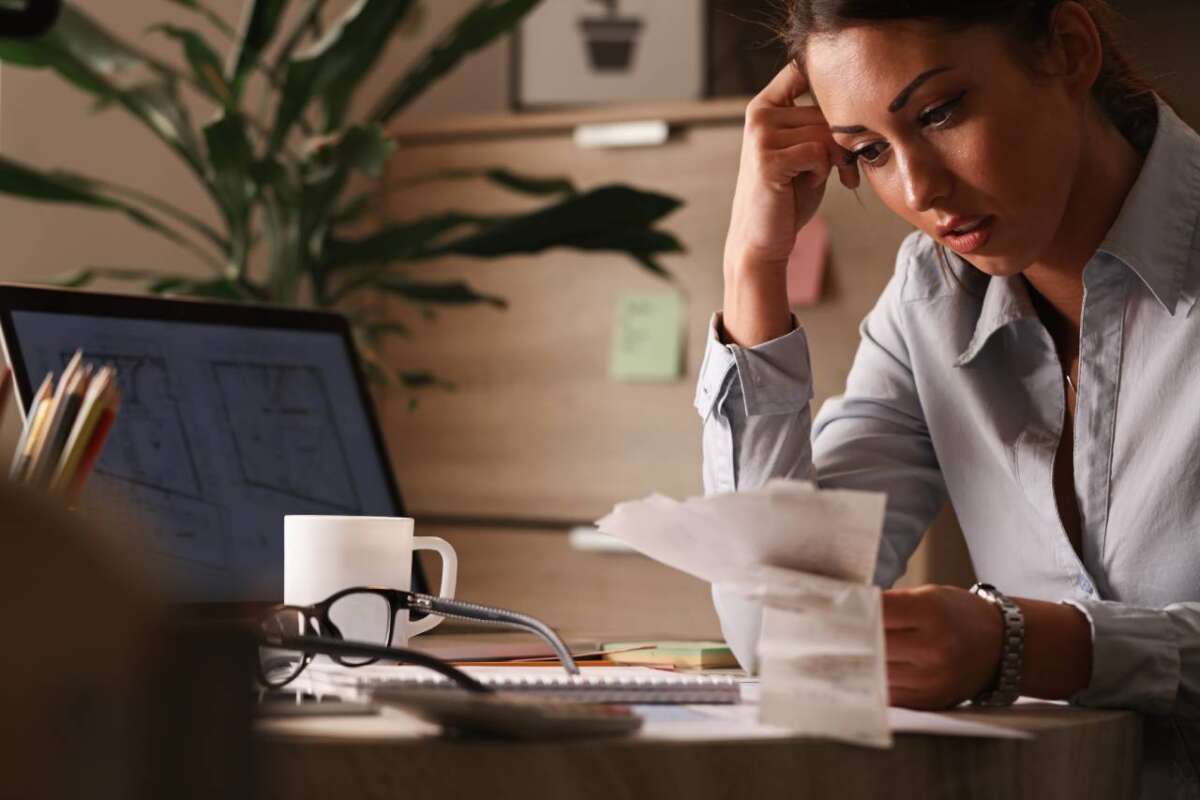 businesswoman-feeling-worried-about-financial-debts-analyzing-bills-while-working-office